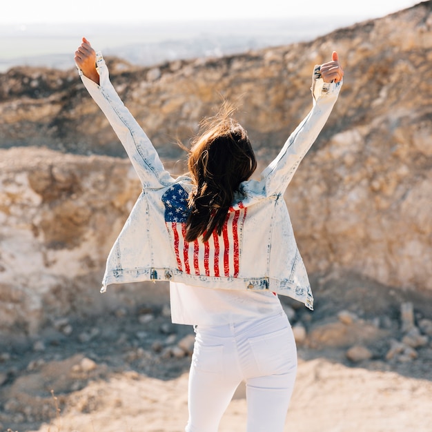 Happy adult woman raising hands on mountain