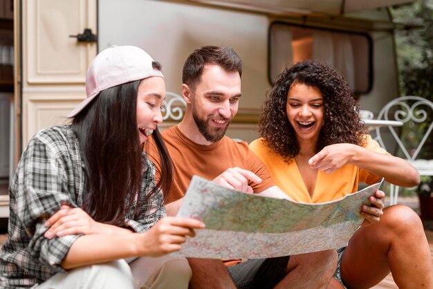 Happy adventurous friends pointing on a map