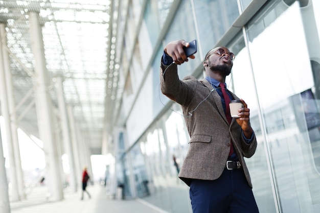 Happy African American business man dances while he listens to the music 