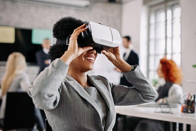 Happy African American businesswoman trying out virtual reality simulator at work