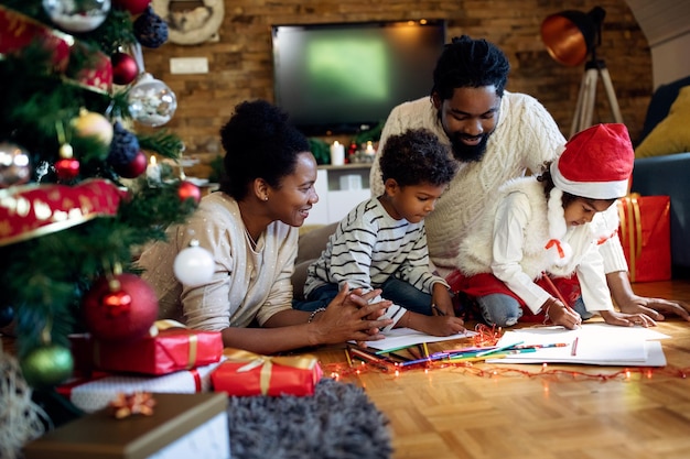 Felice famiglia afroamericana che disegna il giorno di natale a casa