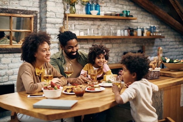 ダイニングテーブルで話している間リラックスして幸せなアフリカ系アメリカ人の家族
