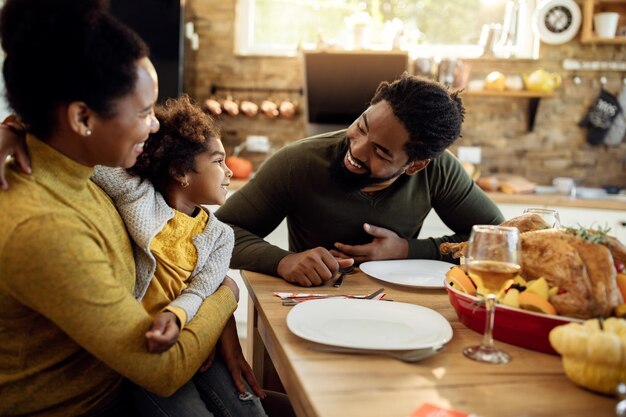Happy African American family talking during Thanksgiving meal in dining room