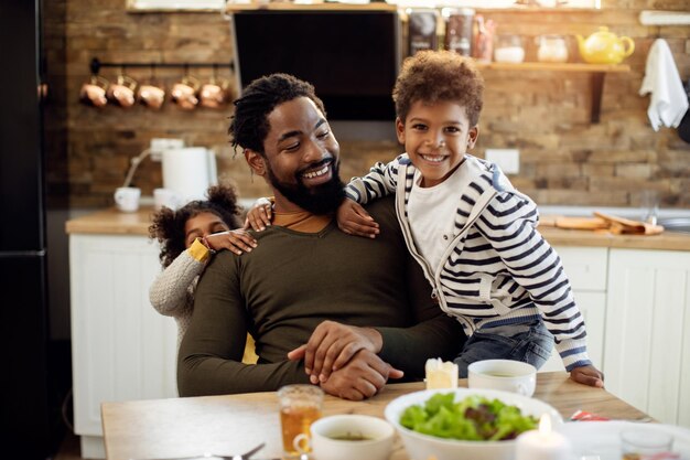Happy African American father having fun with his children in dining room