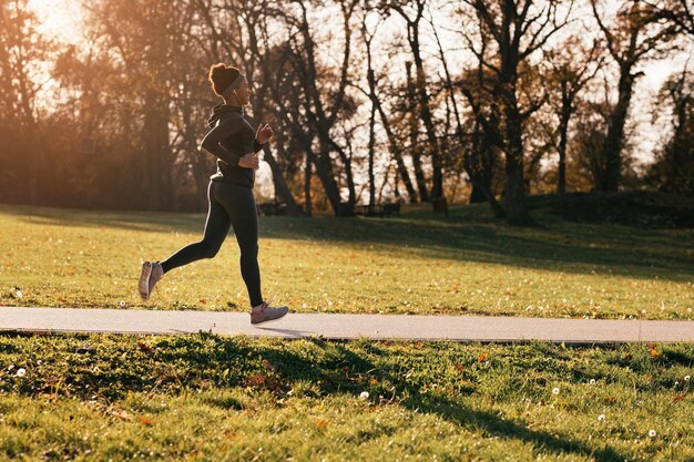 Happy African American female athlete running in the park Copy space