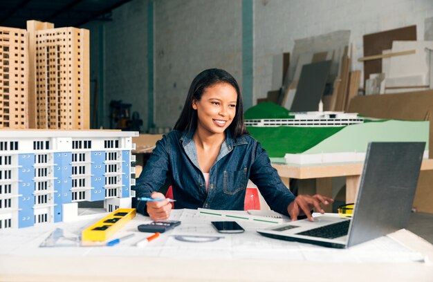 Счастливый афро-американских леди с ноутбуком и модель здания за столом