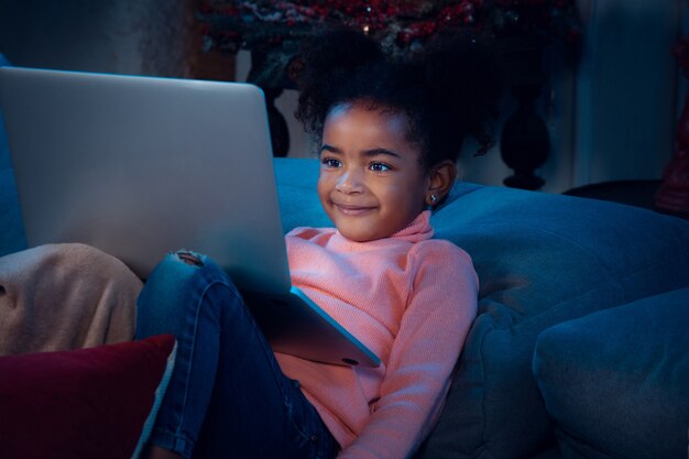 Happy african-american little girl during video call with laptop