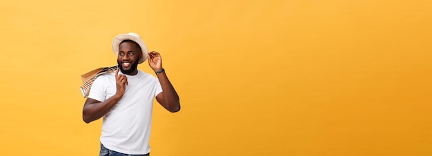 Happy african american man holding shopping bags on yellow background holidays concept