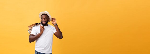 Happy african american man holding shopping bags on yellow background holidays concept