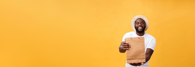 Happy african american man holding shopping bags on yellow background holidays concept