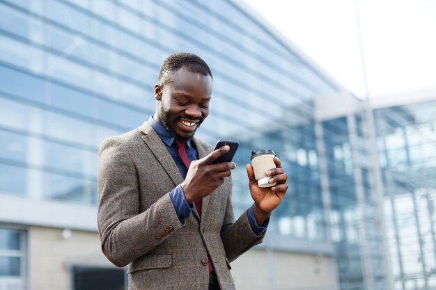 Happy African American man looks lucky reading something in his smartphone 