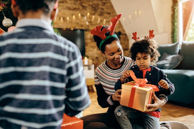 Happy African American mother and daughter with Christmas present at home