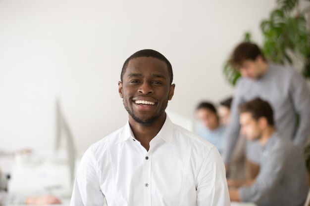 Счастливый афро-американский профессиональный менеджер, улыбаясь, глядя на камеру, выстрел в голову портрет