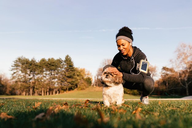 자연 속에 있는 동안 그녀의 작은 개를 껴안고 있는 행복한 아프리카계 미국인 운동가