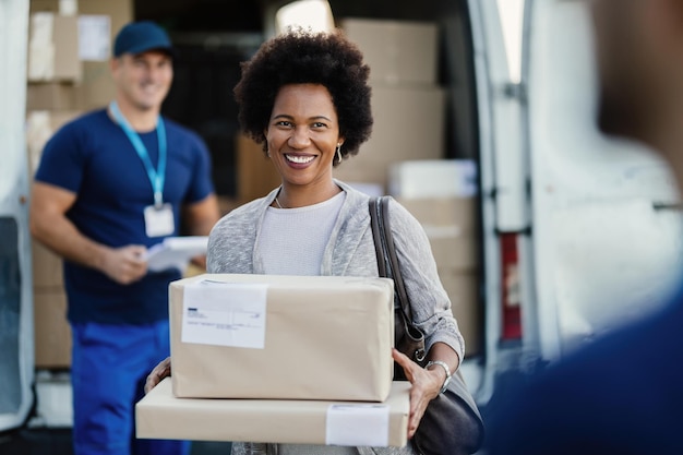 Happy African American woman holding delivered packages A couriers is standing in the background