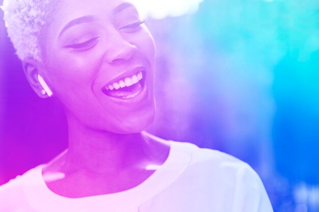 Счастливая афро-американская женщина, слушающая музыку с беспроводными наушниками