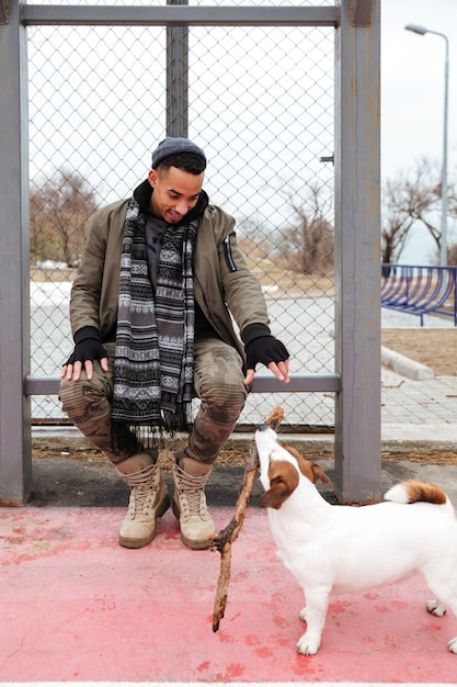 屋外の犬と遊んで幸せなアフリカ系アメリカ人の若い男