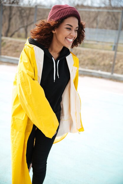 Happy african curly young lady wearing yellow coat