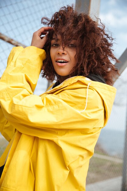 Happy african curly young lady wearing yellow coat