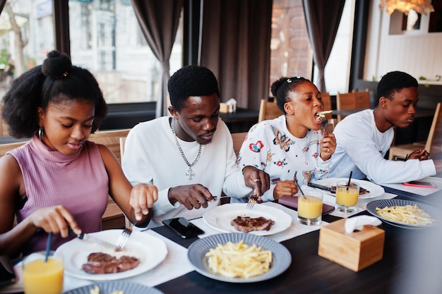 Happy african friends sitting chatting in cafe and eat food Group of black peoples meeting in restaurant and have dinner