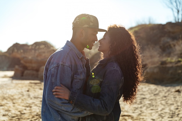 Happy african loving couple hugging outdoors at beach