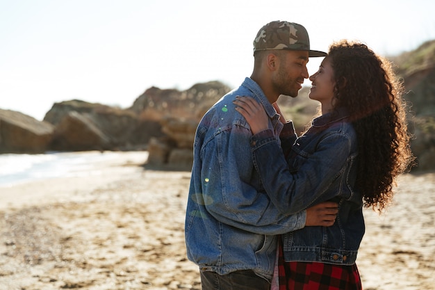 Happy african loving couple hugging outdoors at beach