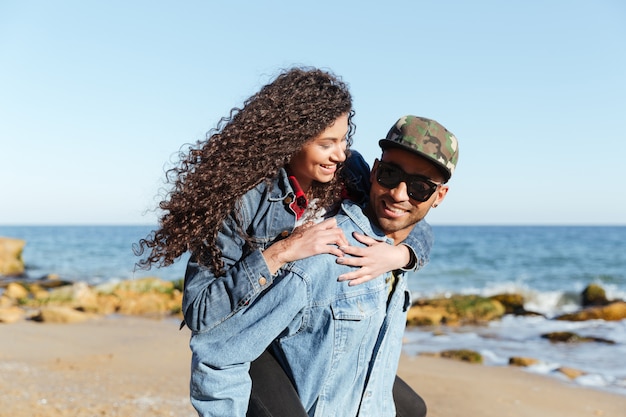 Happy african loving couple walking outdoors at beach