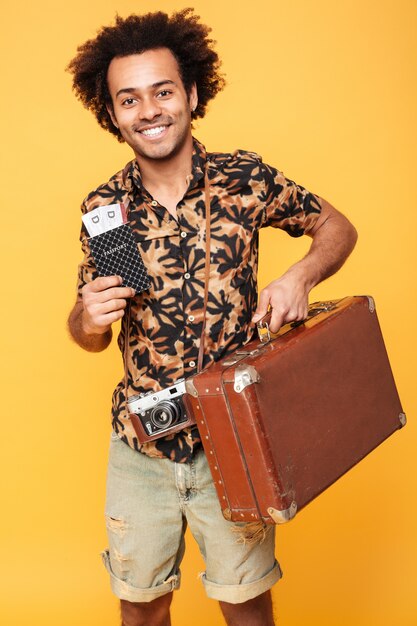 Happy african man holding passport and suitcase.