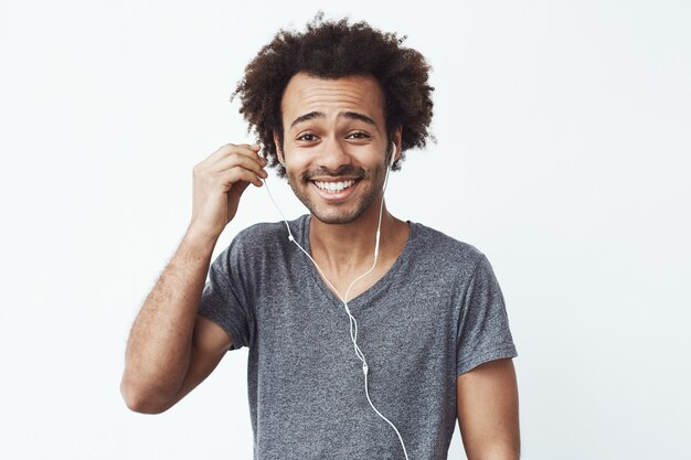 Happy african man putting out headphone smiling.