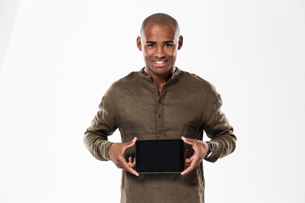 Happy african man showing blank tablet computer screen and looking