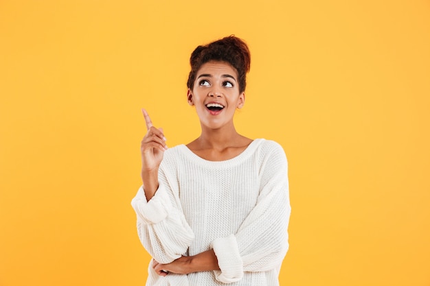 Happy afro-american lady pointing with finger up to copy space