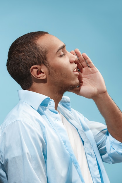 Happy Afro-American man is shouting against blue space