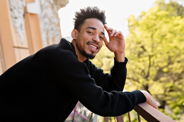 happy afro american man wearing black pullover posing on outdoor terrace.