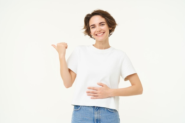 無料写真 幸せで健康な若い女性が左を指し、お腹に触れて気分が良くなった広告を表示