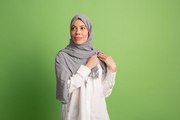 Hijab에서 행복 한 아랍 여자입니다. 녹색 스튜디오 배경에서 포즈 웃는 소녀의 초상화.