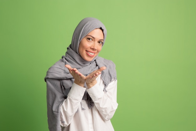 Hijab에서 행복 한 아랍 여자입니다. 녹색 스튜디오 배경에서 포즈 웃는 소녀의 초상화.