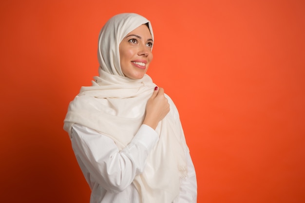 Felice donna araba in hijab. ritratto di ragazza sorridente, che propone al fondo rosso dello studio. giovane donna emotiva. emozioni umane, concetto di espressione facciale.