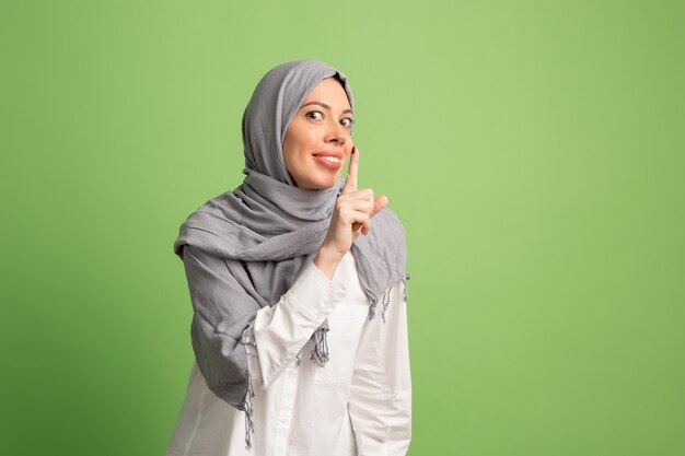 ヒジャーブで幸せなアラブの女性。スタジオの背景でポーズをとって、笑顔の女の子の肖像画