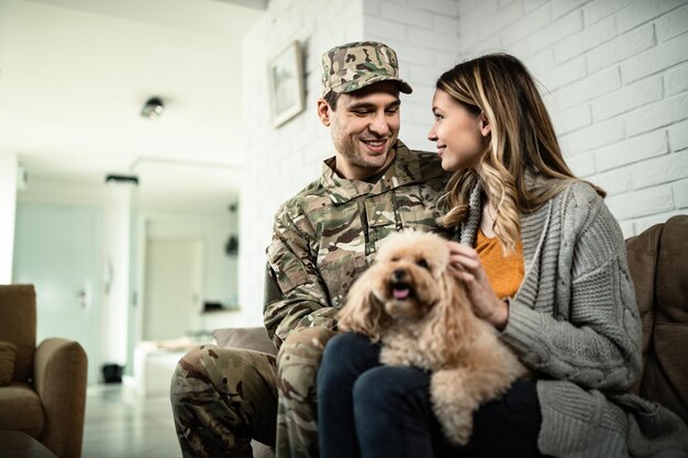 Счастливый армейский солдат и его жена общаются, отдыхая дома со своей собакой