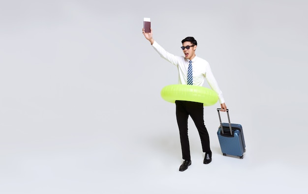 Счастливый азиатский бизнесмен с паспортом и багажом, наслаждаясь их бегством летних каникул.