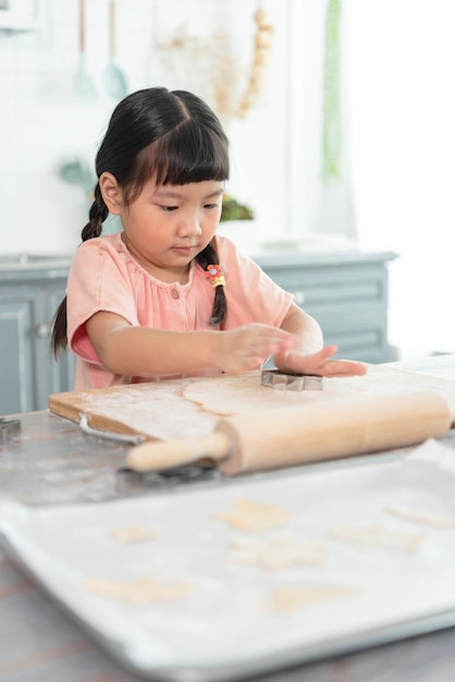 행복한 아시아 아이가 부엌에서 반죽을 굽고 쿠키를 준비하고 있다