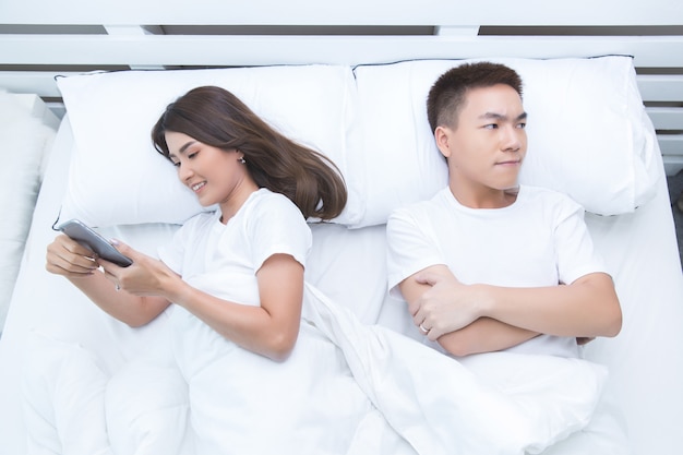 Happy asian couple on the bed at home