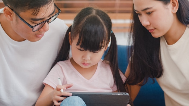행복 한 아시아 가족 아빠, 엄마와 딸 집에서 거실에 소파에 앉아 컴퓨터 태블릿 기술을 사용하여