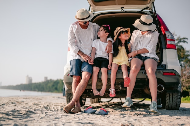 Счастливая азиатская семья, наслаждающаяся пляжной поездкой со своим любимым автомобилем родители и дети путешествуют
