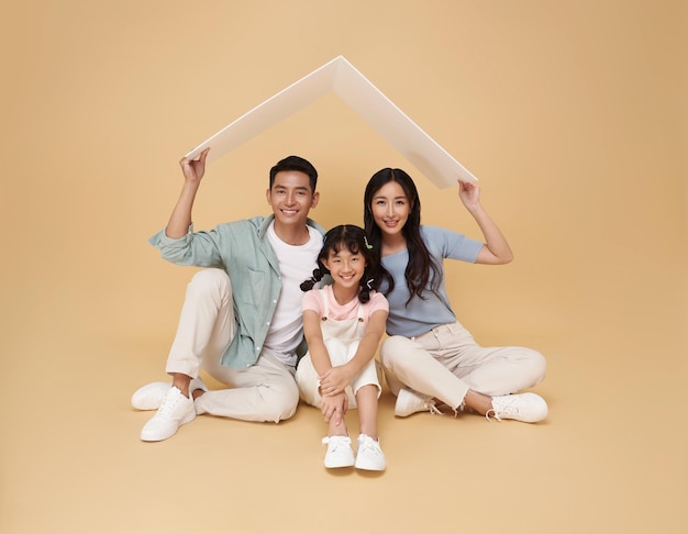 Free photo happy asian family father and mother making roof above their daughter