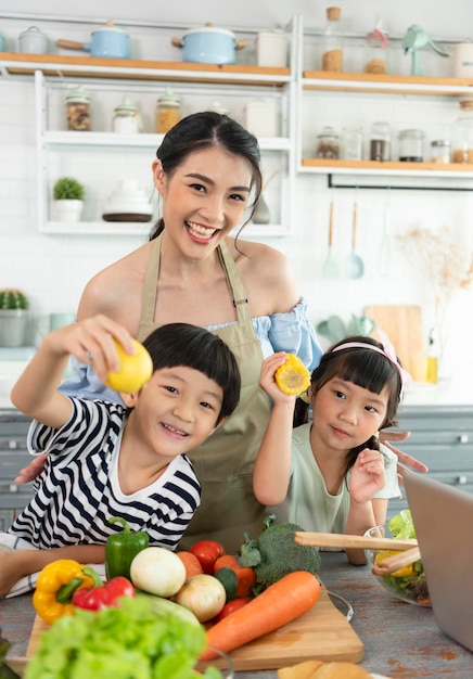 自宅のキッチンで料理を作る幸せなアジアの家族一緒に家族の活動をお楽しみください