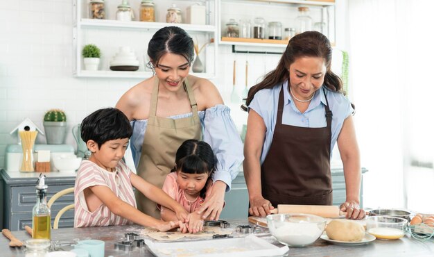 Happy Asian family making preparation dough and bake cookies in kitchen at home