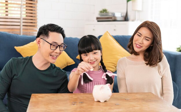 Happy Asian family saving money in piggy bank pig. investment for future concept.