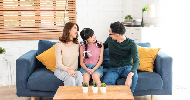 행복한 아시아 가족은 집 거실에 있는 소파에서 함께 이야기를 나눕니다.