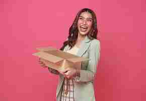 Free photo happy asian girl holding package parcel open boxs isolated on pink background